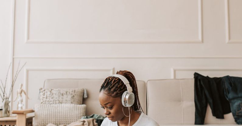 Clothes Packing - A Woman Wearing Her Headphones and Using Her Laptop