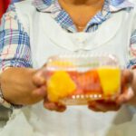 Snack Box - A woman holding a fruit in a market