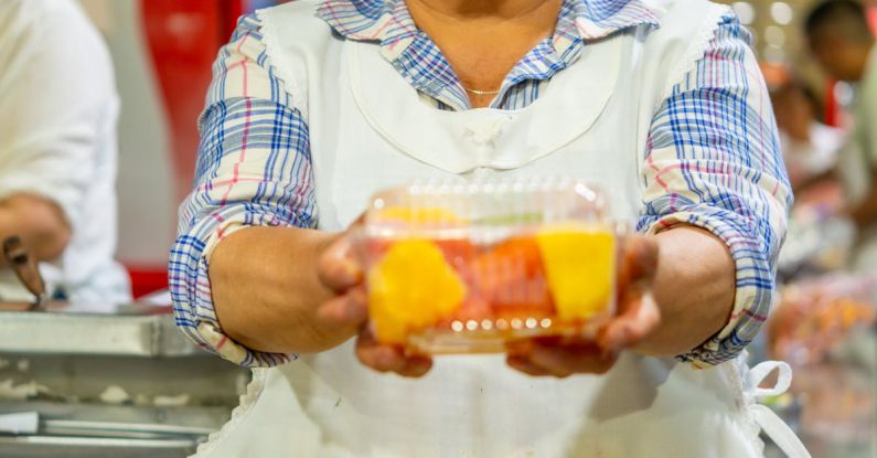 Snack Box - A woman holding a fruit in a market