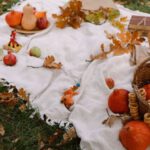 Top Products - From above of ripe exotic red kuri squashes with pumpkins and wicker basket with fresh bread arranged on blanket with books and scattered dry leaves in autumn park