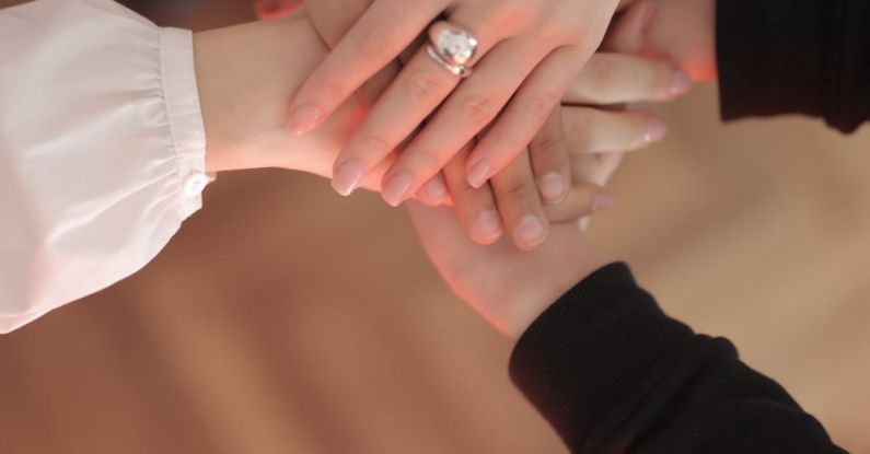 Best Deals - Top view of faceless friends in different clothes stacking hands together while standing on wooden floor indoor on sunny day