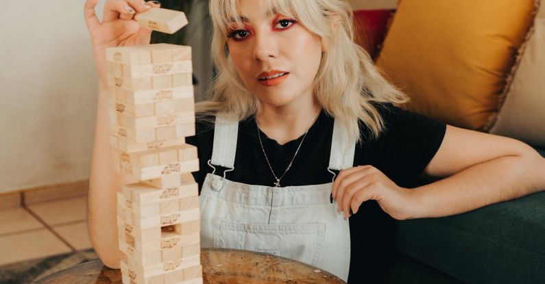 Game Changers - A woman sitting on a couch with a giant wooden tower