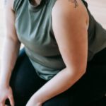 Fitness Revolution - Overweight woman sitting on floor in gym near battle ropes