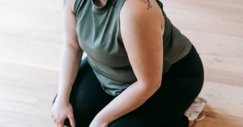 Fitness Revolution - Overweight woman sitting on floor in gym near battle ropes