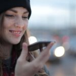 Fashion Apps - Joyful young woman phoning on street in evening