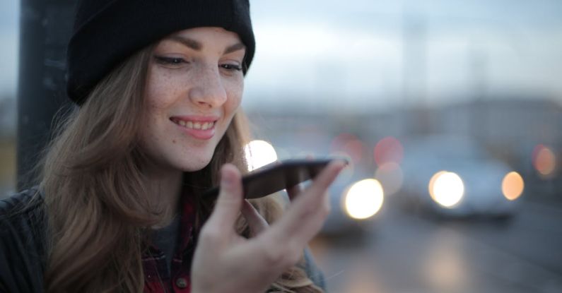 Fashion Apps - Joyful young woman phoning on street in evening