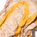 Eco Packaging - Top view of crumpled empty craft paper bag of fast food restaurant placed on white background illustrating recycle garbage concept