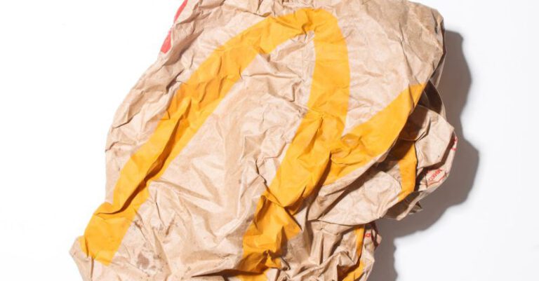 Eco Packaging - Top view of crumpled empty craft paper bag of fast food restaurant placed on white background illustrating recycle garbage concept