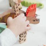 Kids Learning Toys - Child Holding Brown and Green Wooden Animal Toys
